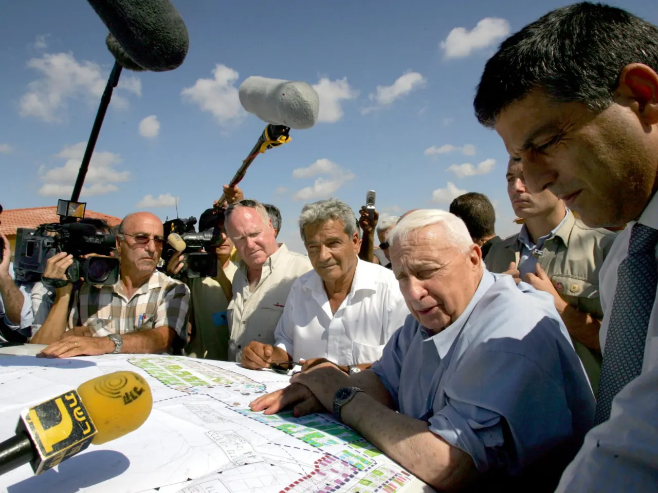 20 years later, Israelis ask if the Gaza exit backfired — and if it's time to go back 3 Israeli Prime Minister Ariel Sharon (second right) is surrounded by reporters on July 5, 2005, as he meets with contractors who are building temporary housing for settlers due to be evacuated from the Gaza Strip under his disengagement plan at the Nitzanim construction site in southern Israel.