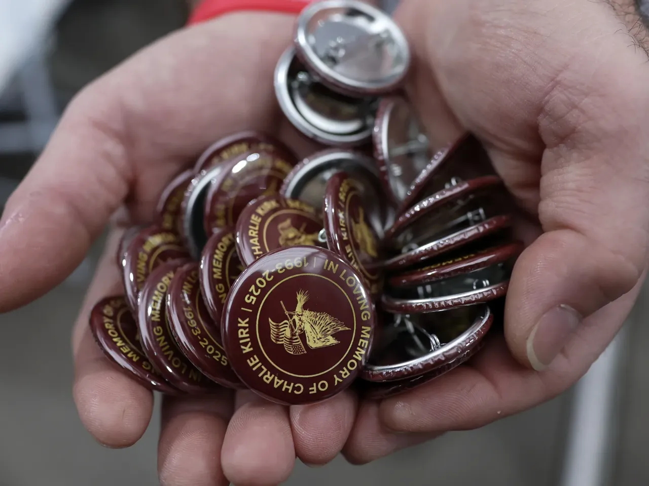 A man carries pins that read: "In loving memory of Charlie Kirk."