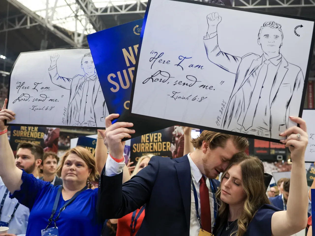 Attendees hold up religious signs at the memorial service for political activist Charlie Kirk.