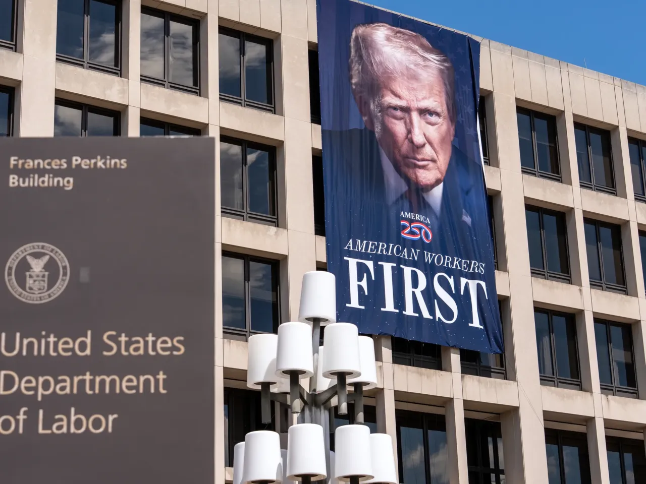 A portrait of President Donald Trump hangs on the Labor Department headquarters in Washington, D.C. on Aug. 25, 2025. The agency is bringing back some workers who took the government's deferred resignation offer. Still other employees whose jobs were eliminated received notices that they would be assigned to new positions.