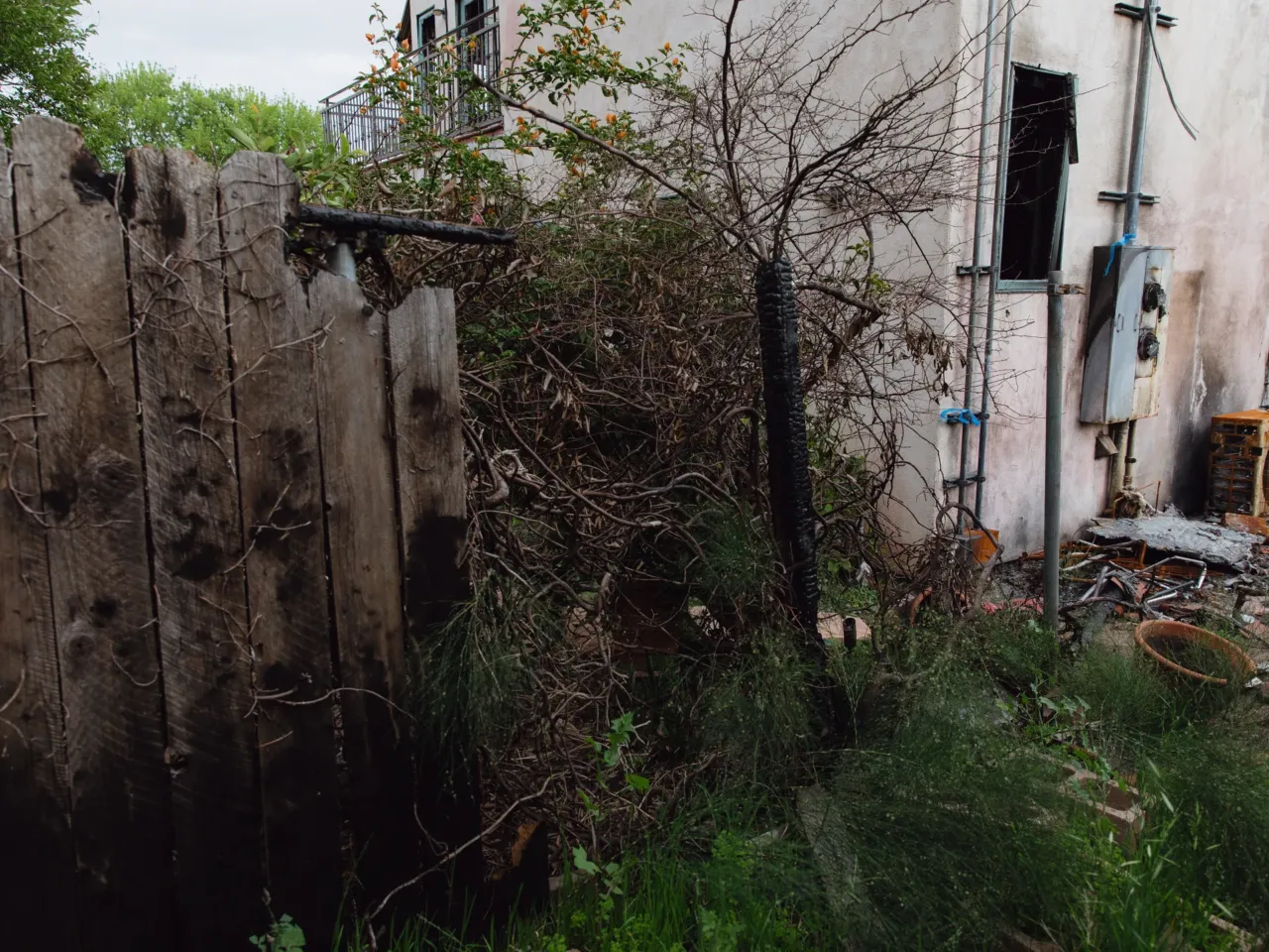 Hours before the Eaton fire, distribution lines failed and fire started in Altadena 4 The damaged fence where the charred utility pole fell stands between Lea Chazin's home and her neighbor's backyard.