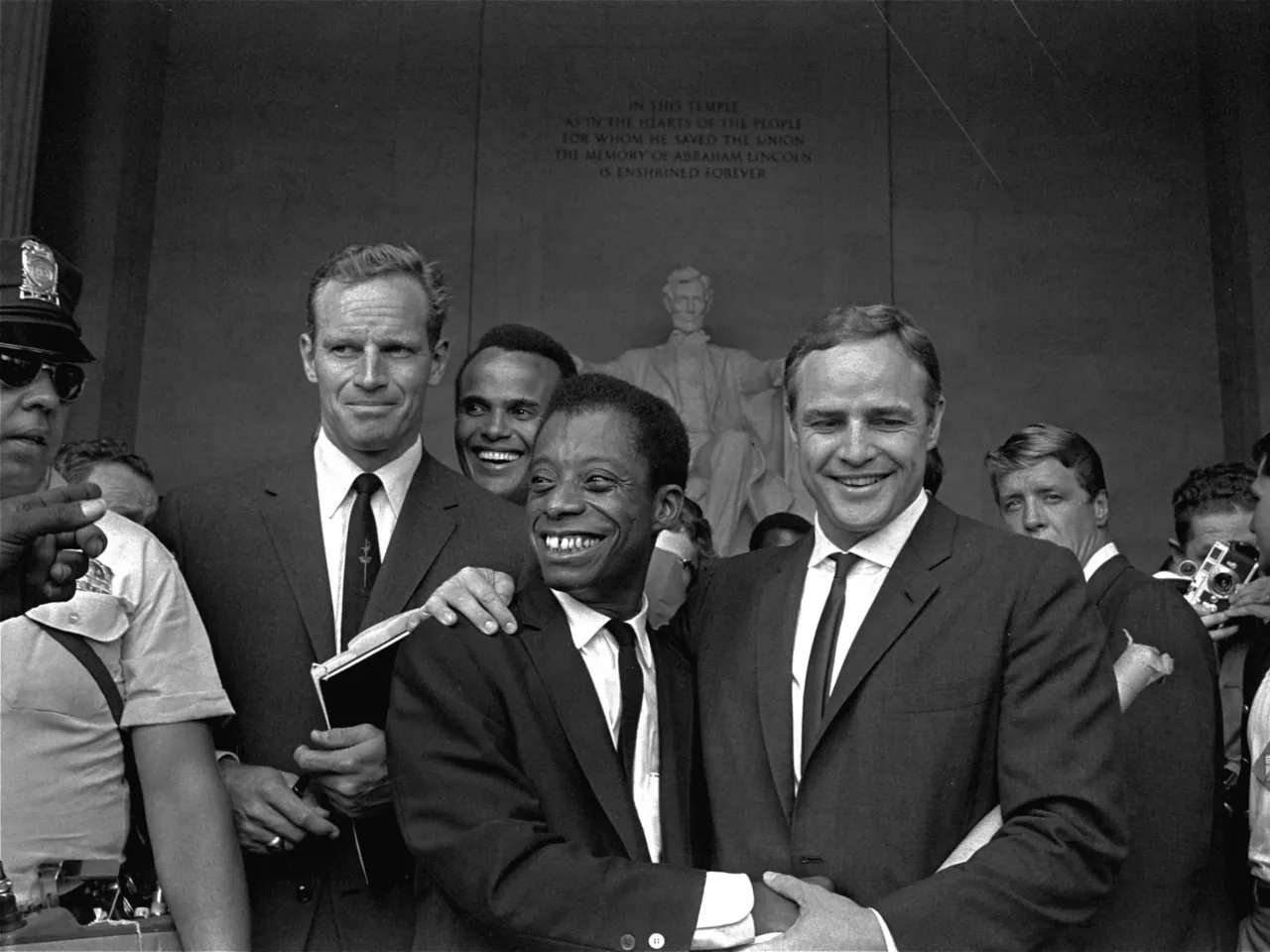 A new James Baldwin biography explores how his lovers influenced his work 2 James Baldwin embraces actor Marlon Brando (right) with actors Charlton Heston (left) and Harry Belafonte stand behind them at the Lincoln Memorial on Aug. 28, 1963, during the March on Washington.