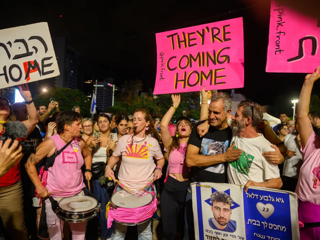 Michel Illouz (L), father of Guy Illouz, and Ilan Dalal, father of hostage Guy Gilboa Dalal (R), embrace and react next to protestors cheering and holding signs that read, "they're coming home"  in Hostages Square, Tel Aviv, on Oct. 11th