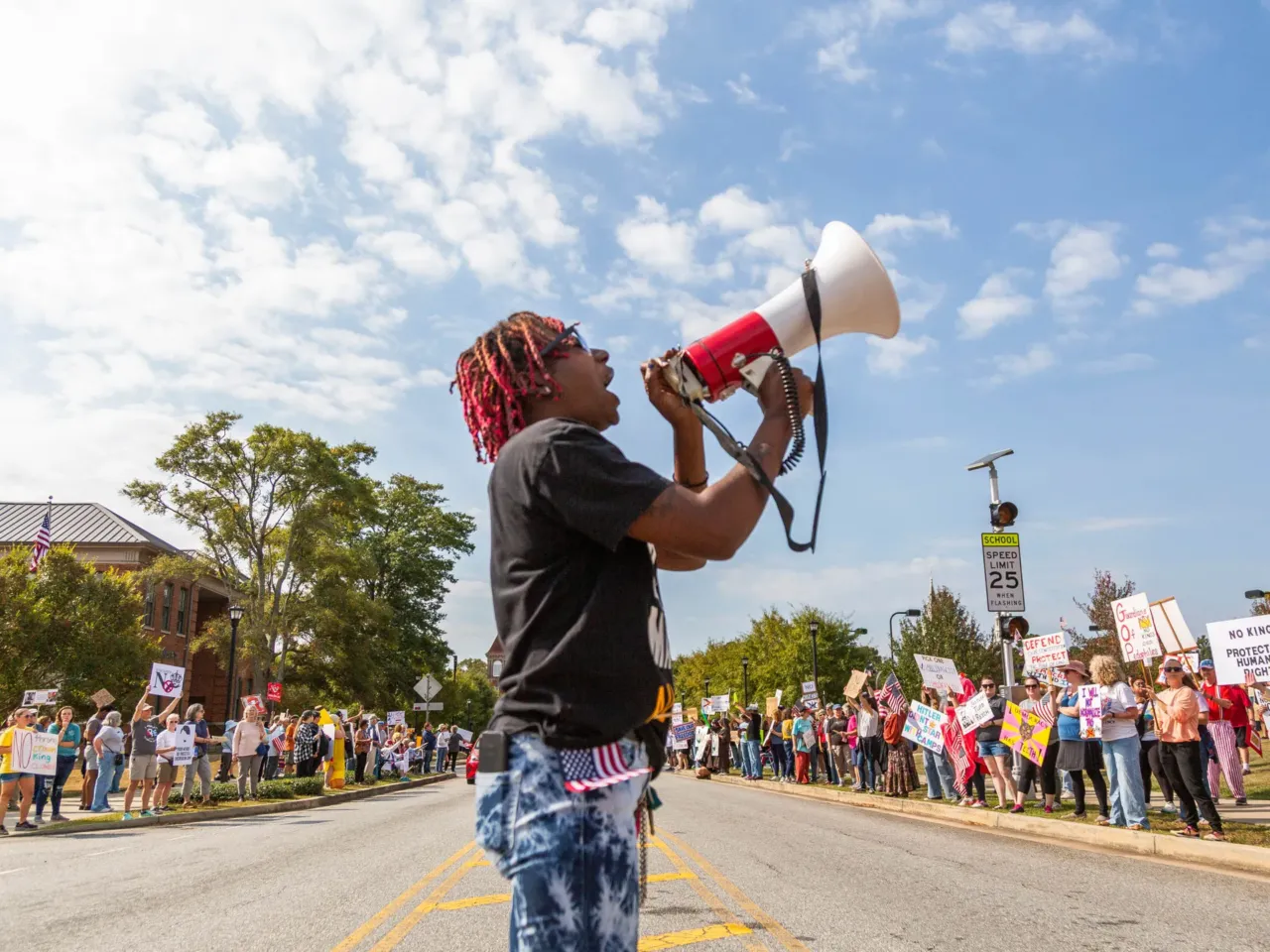 Legacee Medina of Macon, Ga. leads chanting at a No Kings rally between an elementary school and pickleball courts in Macon on October 18, 2025. The rally moved from its earlier location downtown to stay out of the way of a planned Hispanic festival.