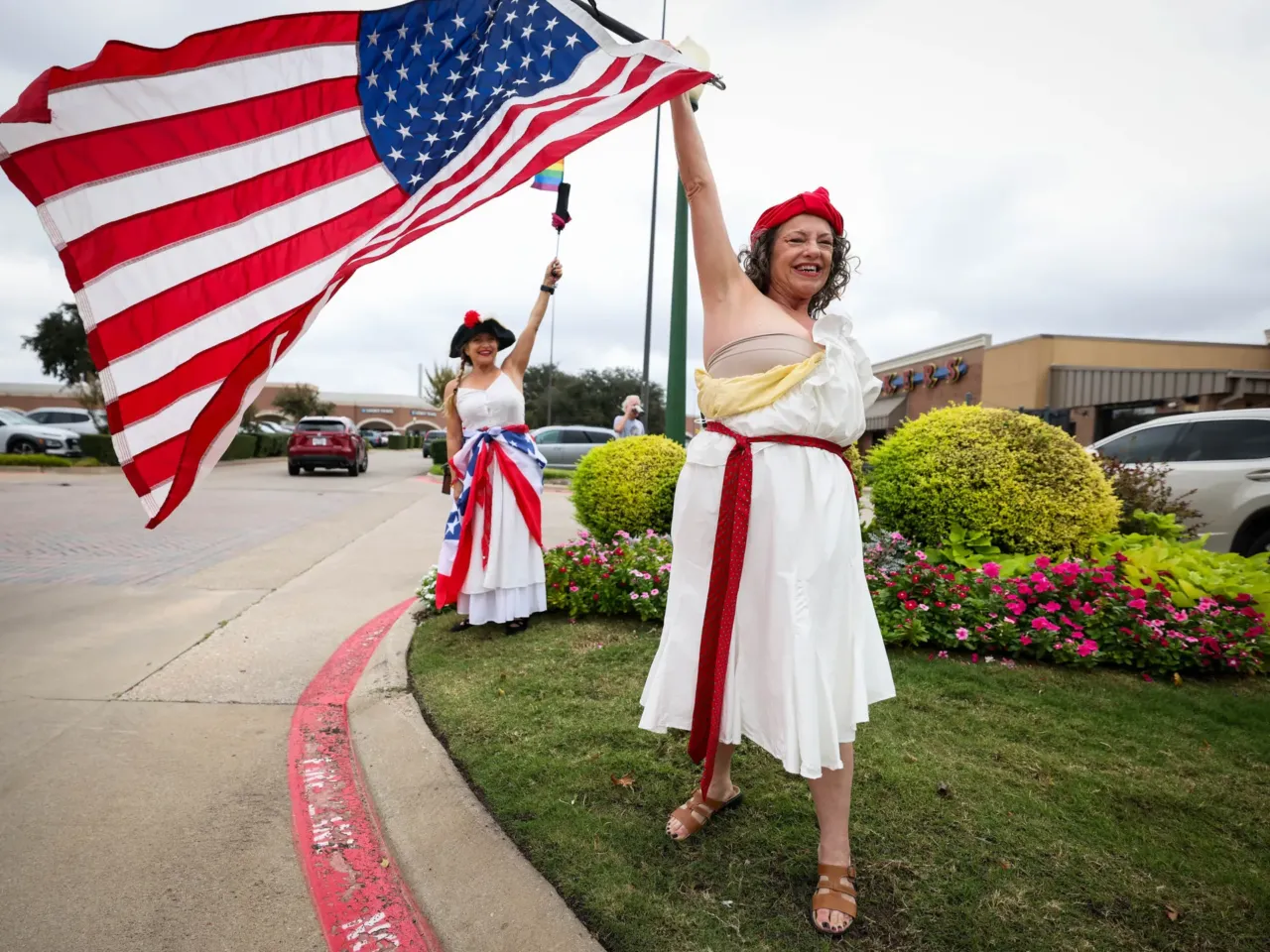 Samantha Shub holds up a flag as the 'No Kings" protest ramps up in Plano, TX.