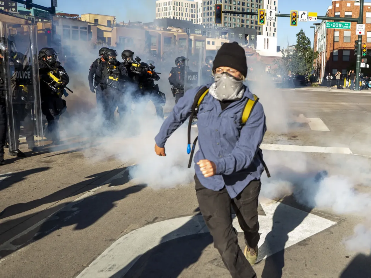 Police officers shoot pepper balls and throw chemical canisters into a small group of protesters who refused to disperse from 20th and Wewatta Streets in Denver after the main No Kings rally ended on Oct. 18, 2025.