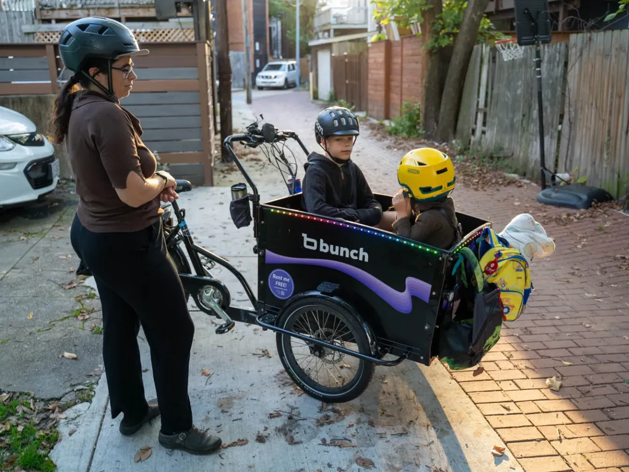 Lelac Almagor waits as her kids get ready for the ride to school. Her cargo bike is technically a trike, with two wheels in front for more stability.
