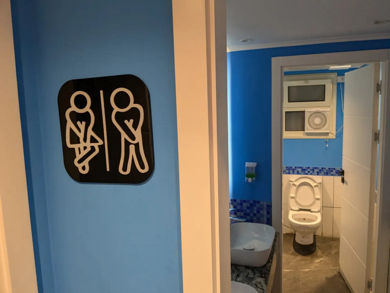 This photo was taken in a café in the neighborhood of Obour city, which is part of greater Cairo, Egypt. The photographer says that the sign serves as a reminder that everyone needs easy access to a toilet.
