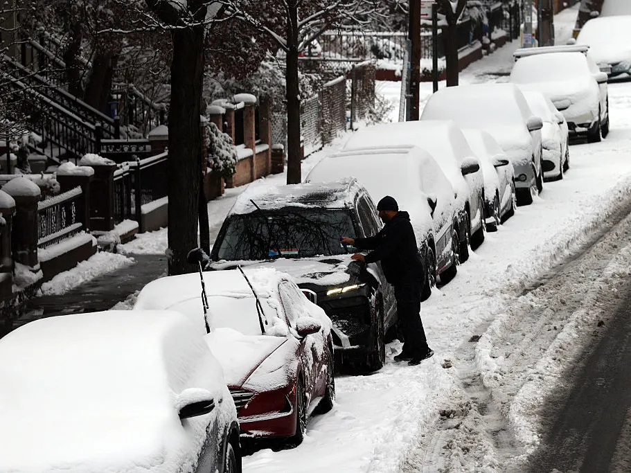 A man cleans off his car of snow in Brooklyn after an overnight storm on Dec. 27, 2025 in New York City.