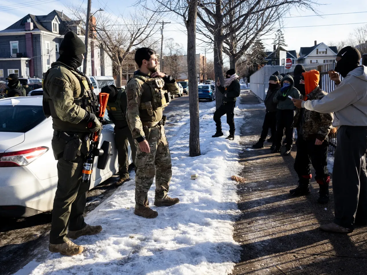 Observers and protesters confront U.S. Customs and Border Protection agents as they check the immigration status of two men in a car in South Minneapolis on Monday, Jan. 12, 2026.
