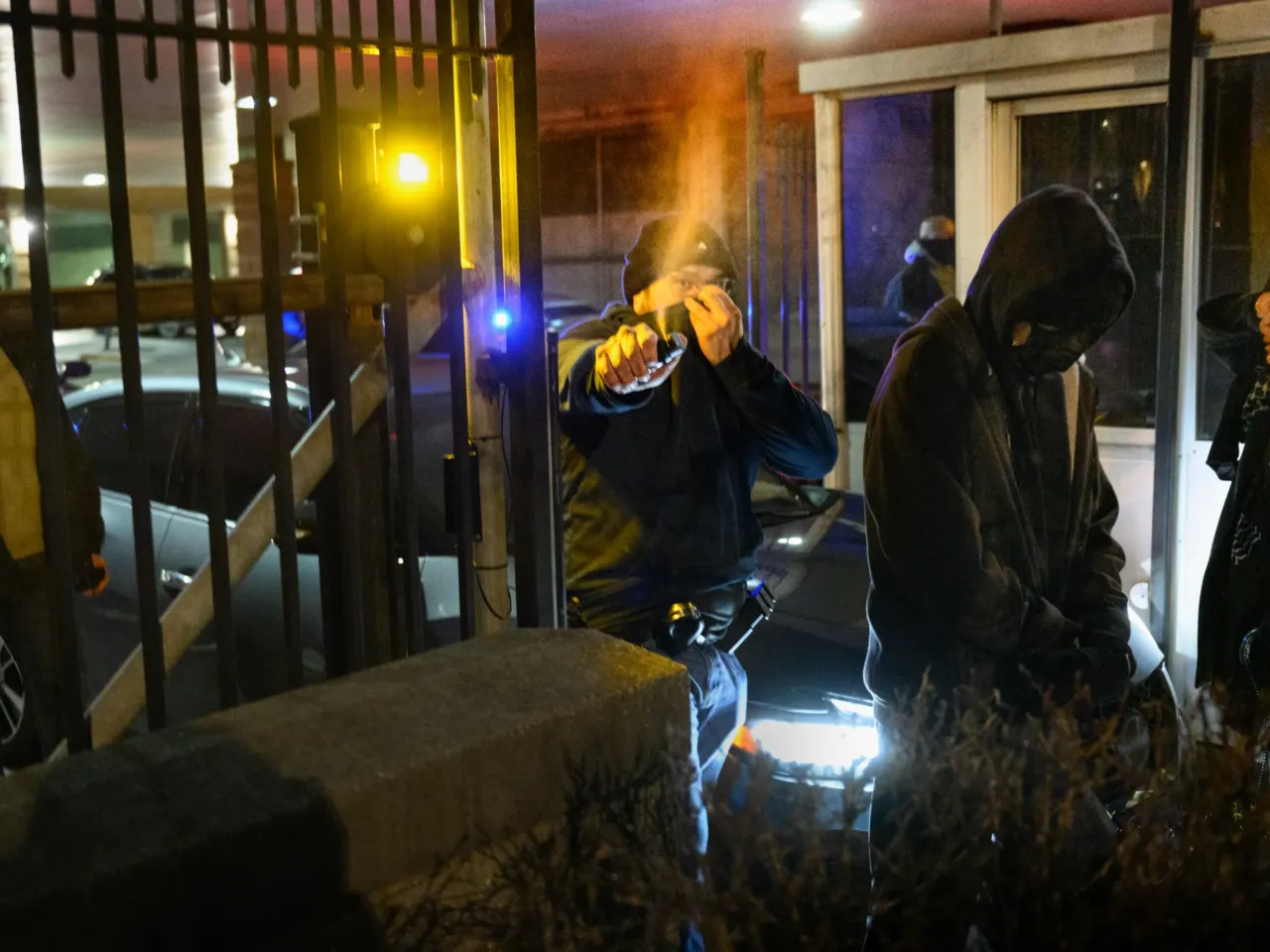 A masked agent sprays chemical irritant from inside the parking garage at the Abraham A. Ribicoff Federal Building and U.S. Courthouse in Harford, Conn. as protesters block cars attempting to exit on Jan. 8.