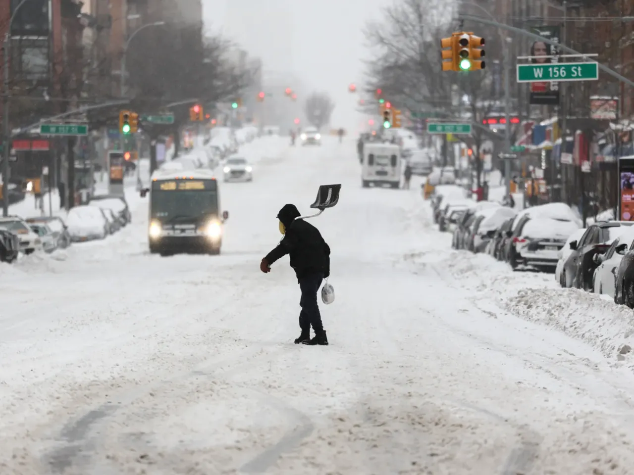 A man carries a shovel as he crosses a street in the Hamilton Heights neighborhood in New York on Sunday.