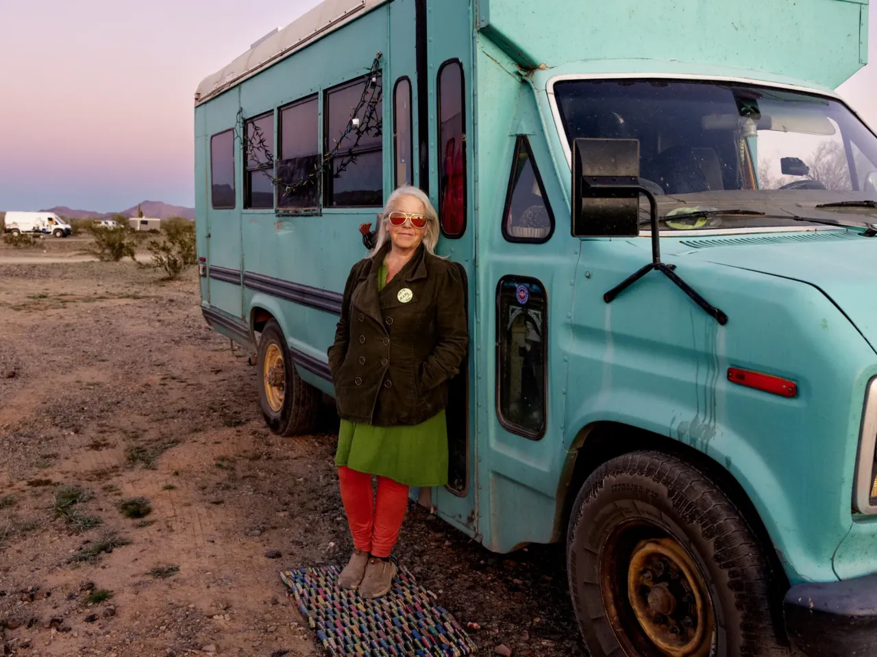 Mary Freuer stands outside of her teal converted school bus, also known as a skoolie.
