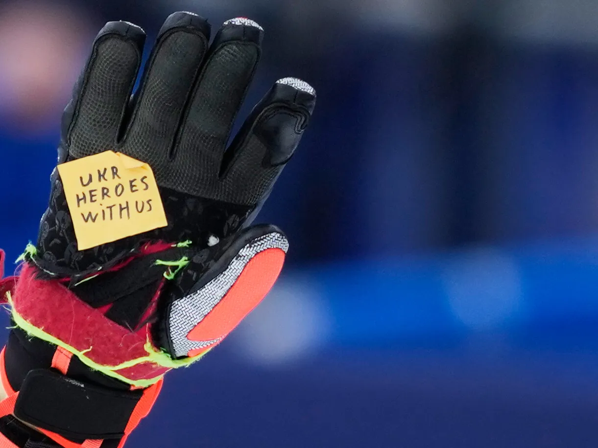 Ukraine's Dmytro Shepiuk holds a sticker reading "UKR heroes with us" at the finish area during a men's super-G race, at the 2026 Winter Olympics, in Bormio, Italy, Wednesday.