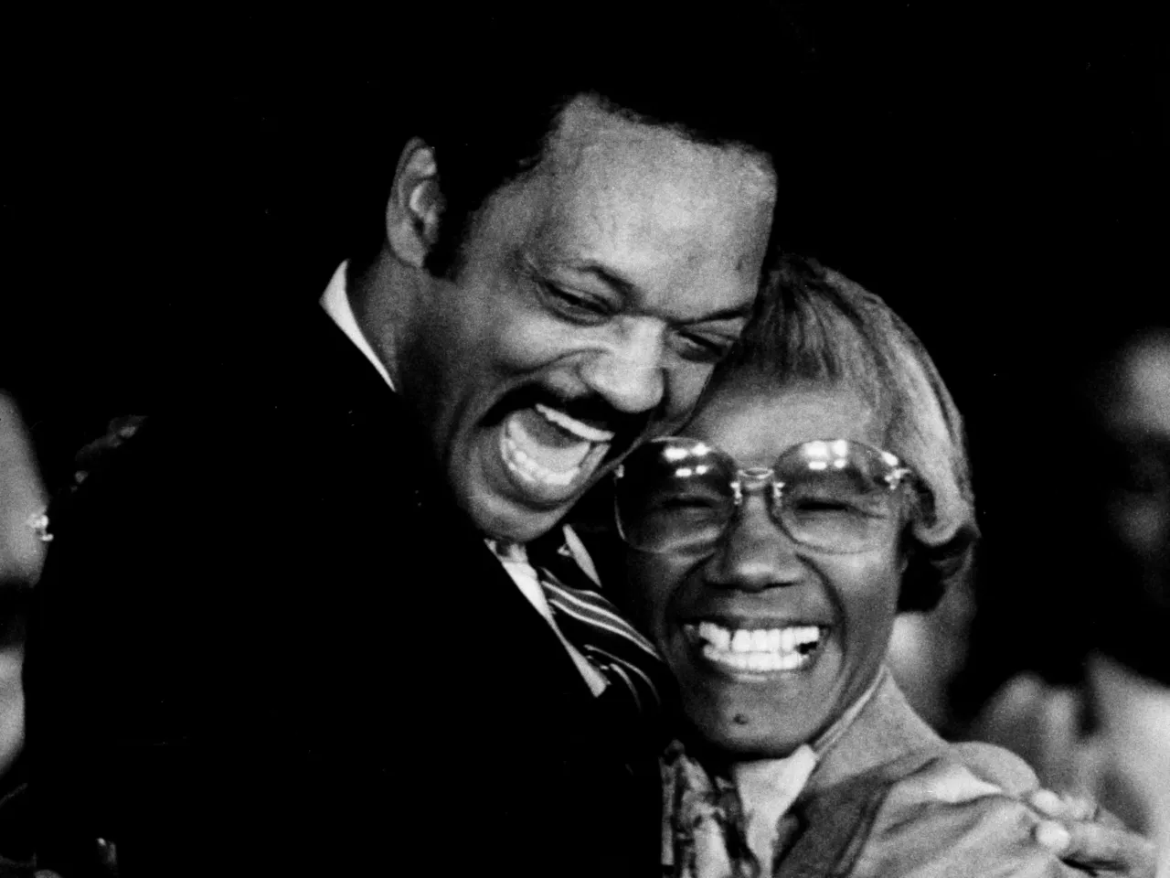 Rev. Jesse Jackson and former Congresswoman Shirley Chisholm hug after he announced that he will run for president in November 1983.