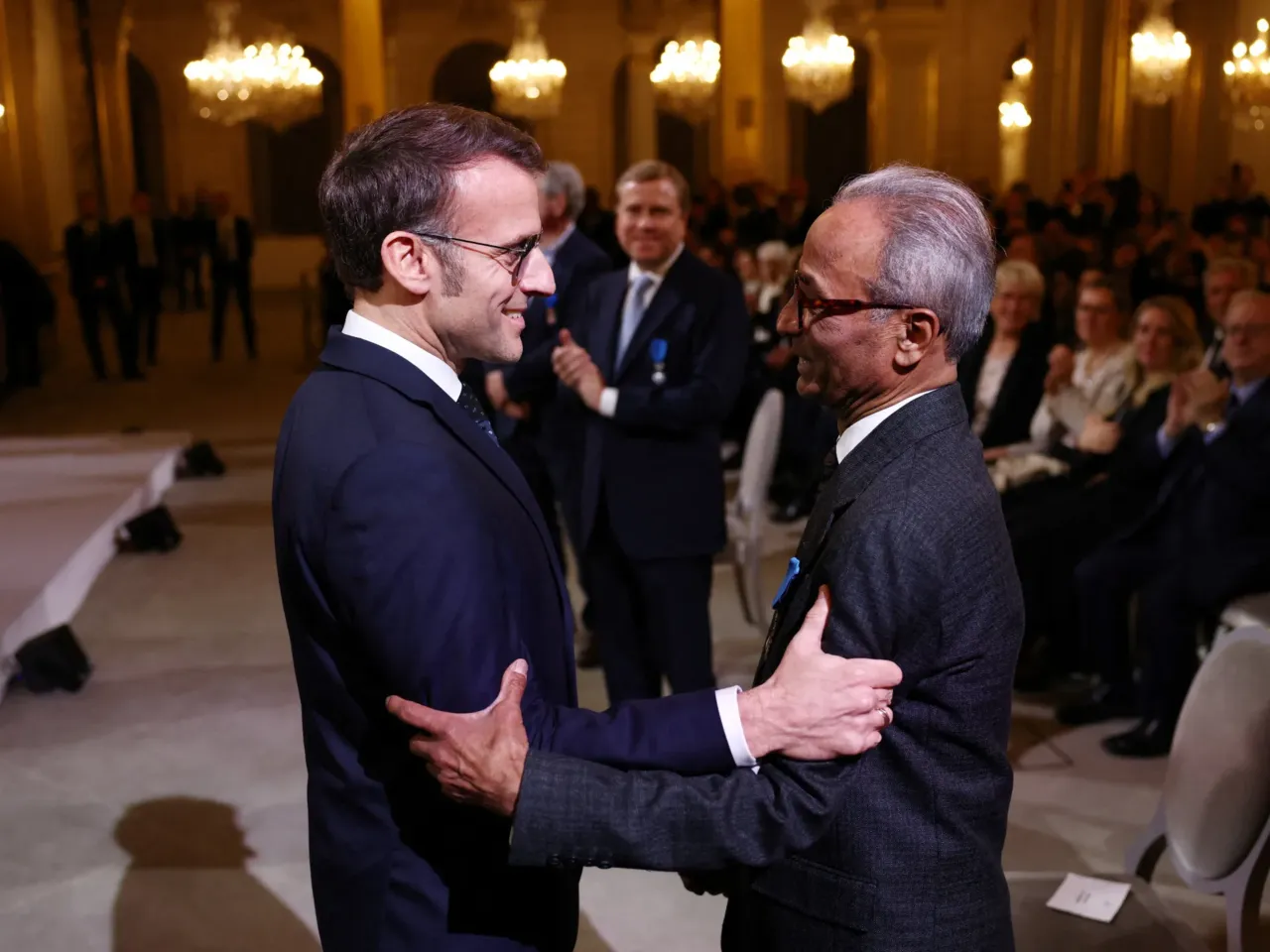French President Emmanuel Macron awards the Chevalier of the French National Order of Merit to Ali Akbar at the Elysee Palace in Paris on Jan. 28, 2026. Akbar, an immigrant from Pakistan, has been selling newspapers around Saint-Germain-des-Pres in the French capital for 50 years.
