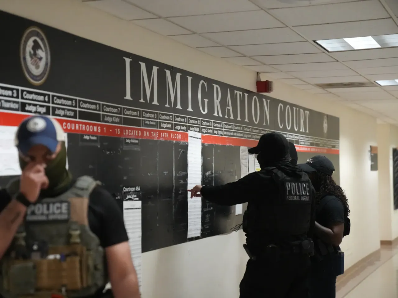 U.S. has a quarter fewer immigration judges than it did a year ago. Here's why 1 U.S. Immigration and Customs Enforcement agents look over lists of names and their hearing times and locations inside the Federal Plaza courthouse before making arrests in June 2025 in New York.