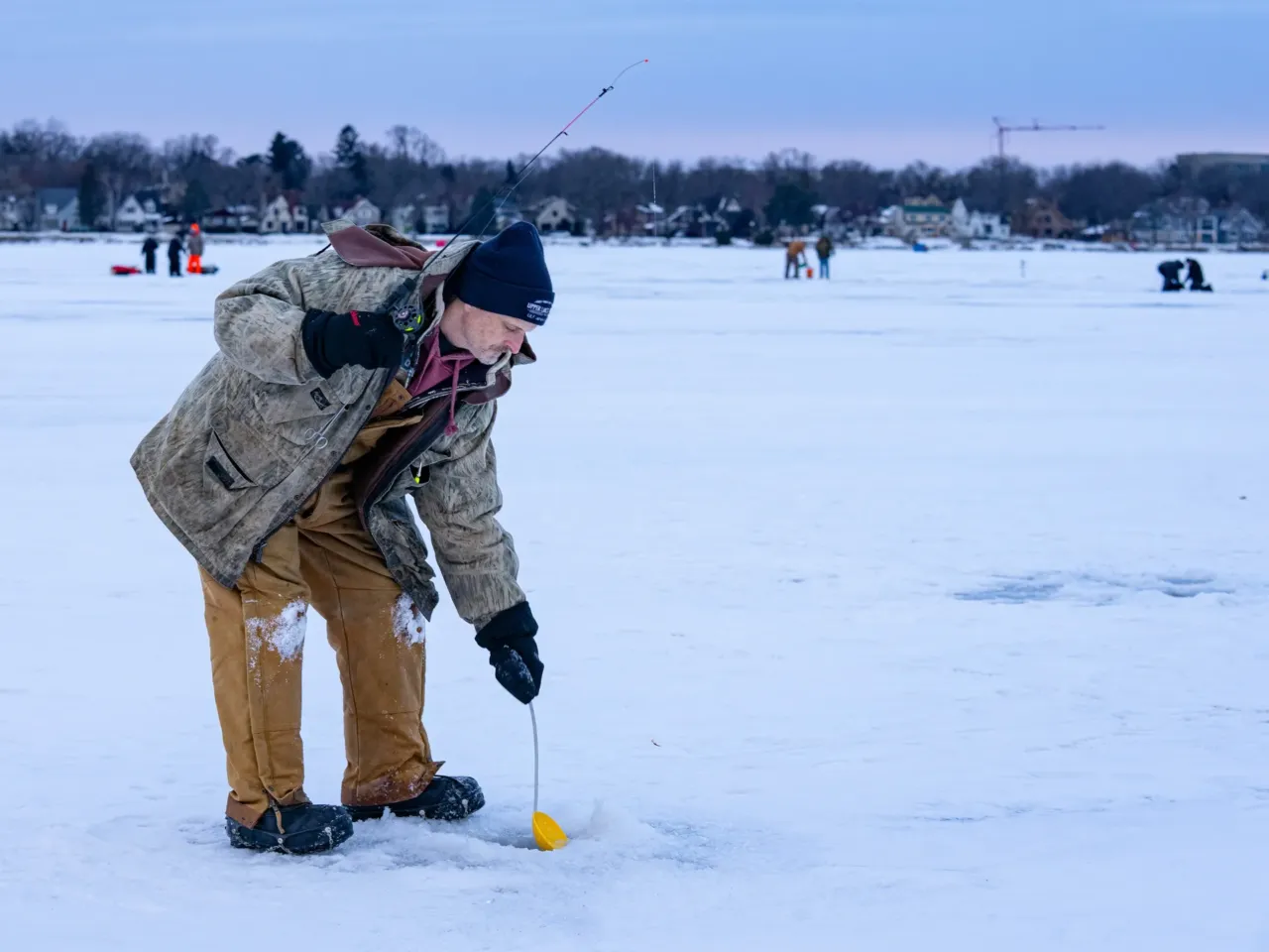 This community festival embraces the joys of a frozen lake — while it still has one 11 Tony Pavlak scoops slush off the water's surface in a hole drilled on Monona Bay while ice fishing.