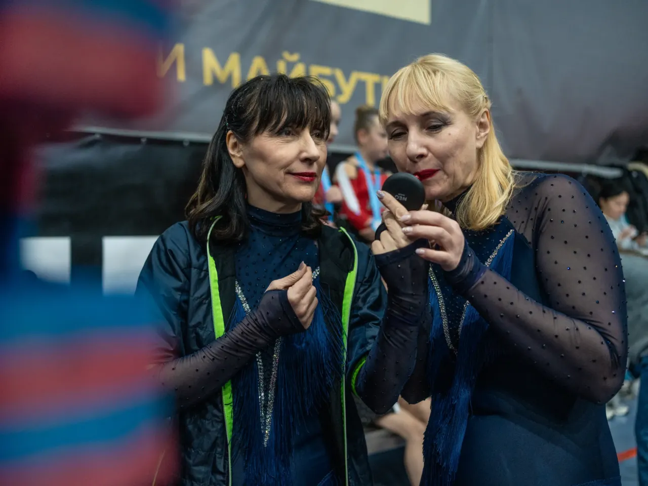 Iryna Nesterenko, 63, (left), captain of the Sunrise cheerleading squad, and team member Olena Zolotchenko, 57, apply makeup before they compete in Kyiv during the Ukraine Cheer Cup competition on Dec. 13, 2025.