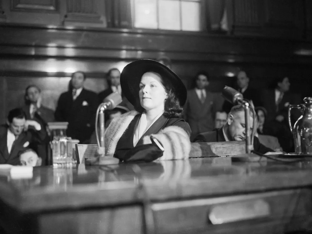 Wearing a mink stole, Virginia Hill Hauser testified before the Kefauver committee. She faced questions about her financial dealings with several key crime figures.
