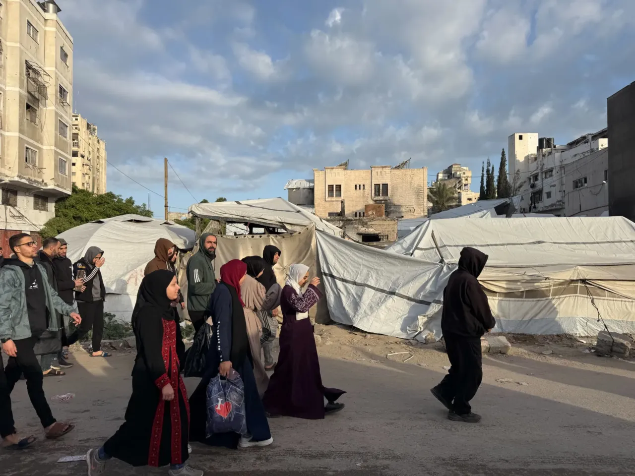 Palestinians celebrate Eid in Gaza, making the most of a fragile ceasefire 3 People walk past tents in Gaza City on Friday as Palestinians there celebrated Eid.