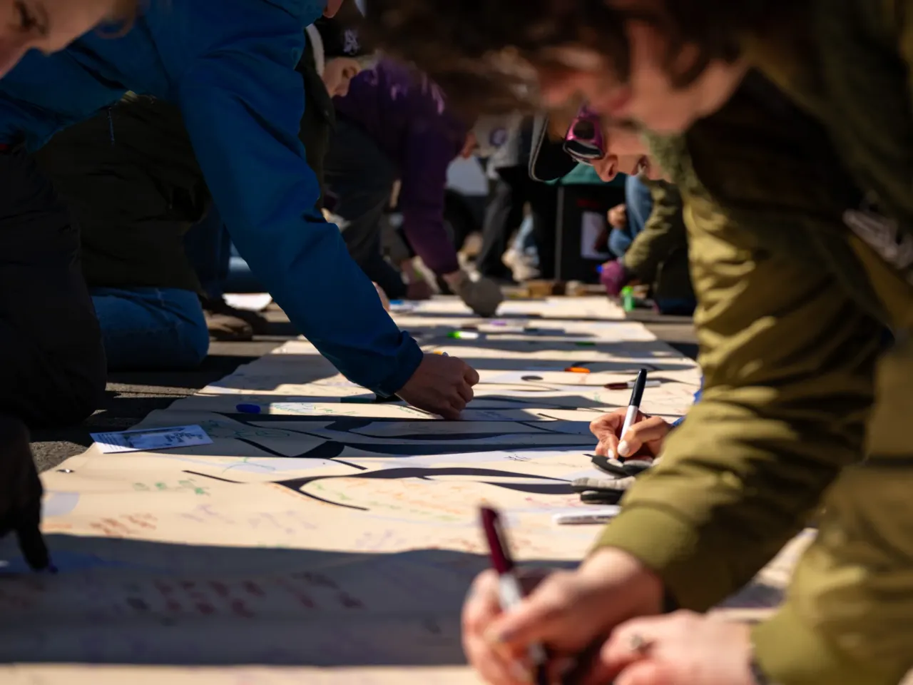 Thousands sign a banner in Hartford at the Capitol that says "We the People."
