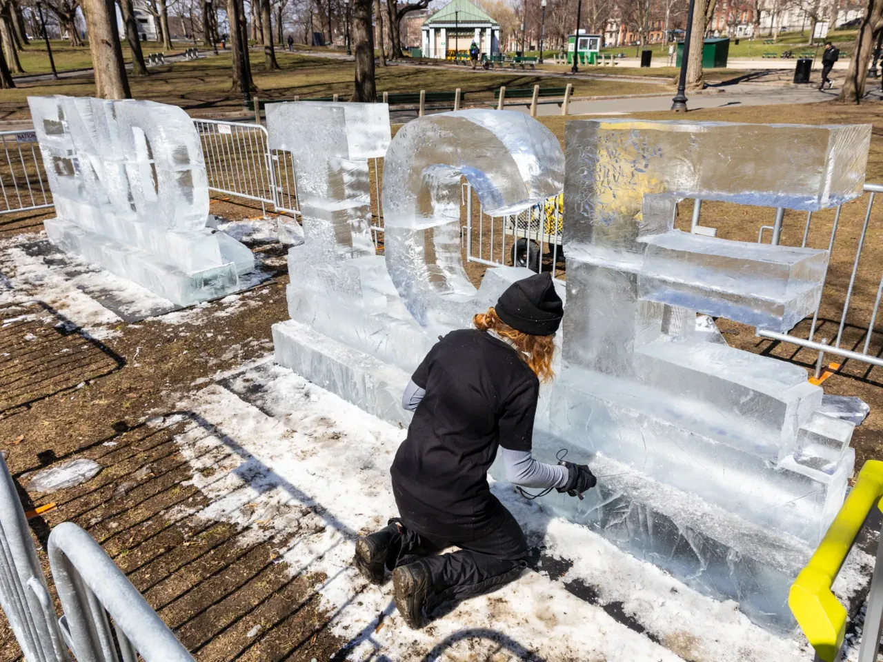 Kat Carves works on a ice sculpture that says 'End Ice' ahead of the rally on the Boston Common in Boston.