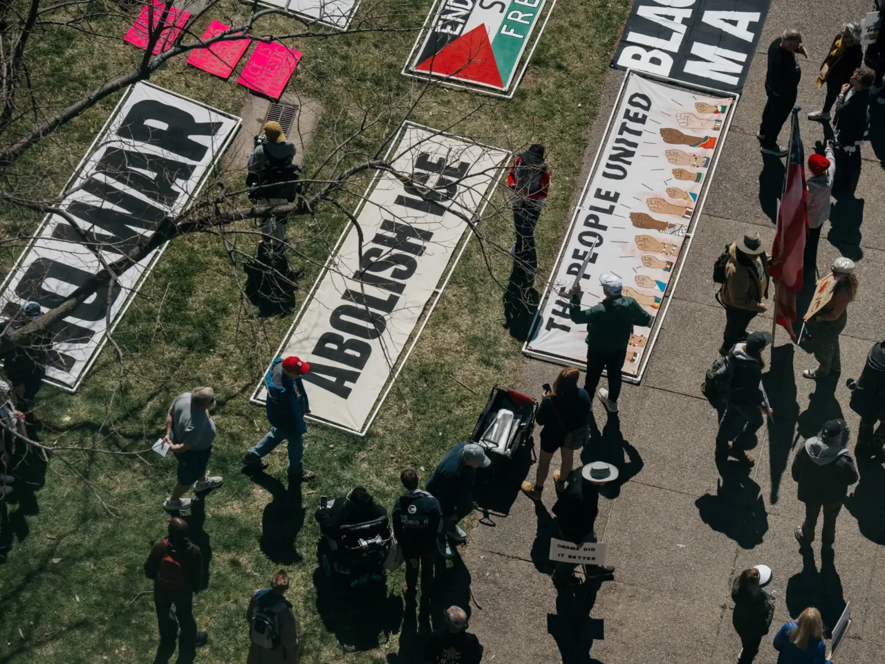 Demonstrators in downtown St. Louis walk by large banners decrying the U.S. conflict in Iran and U.S. Immigration and Customs Enforcement.