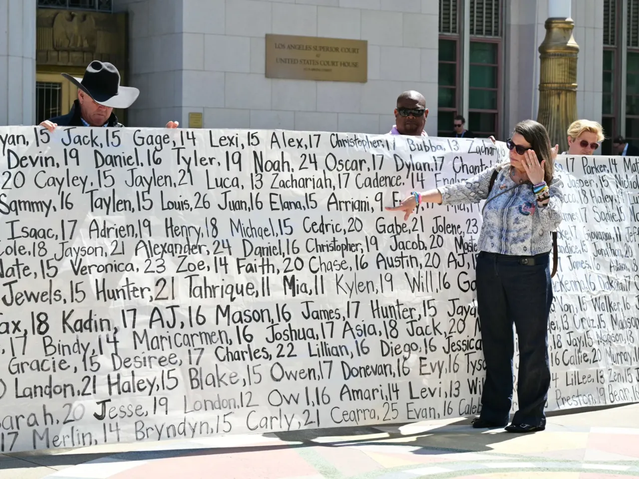 Mary Rodee, whose 15-year-old son died by suicide, points to a banner listing victims' names outside Los Angeles Superior Court on March 25, 2026, after a jury found Meta and YouTube liable for harming a young woman through the addictive design of their social media platforms. The landmark verdict could reshape how the tech industry faces legal accountability for harms to users.