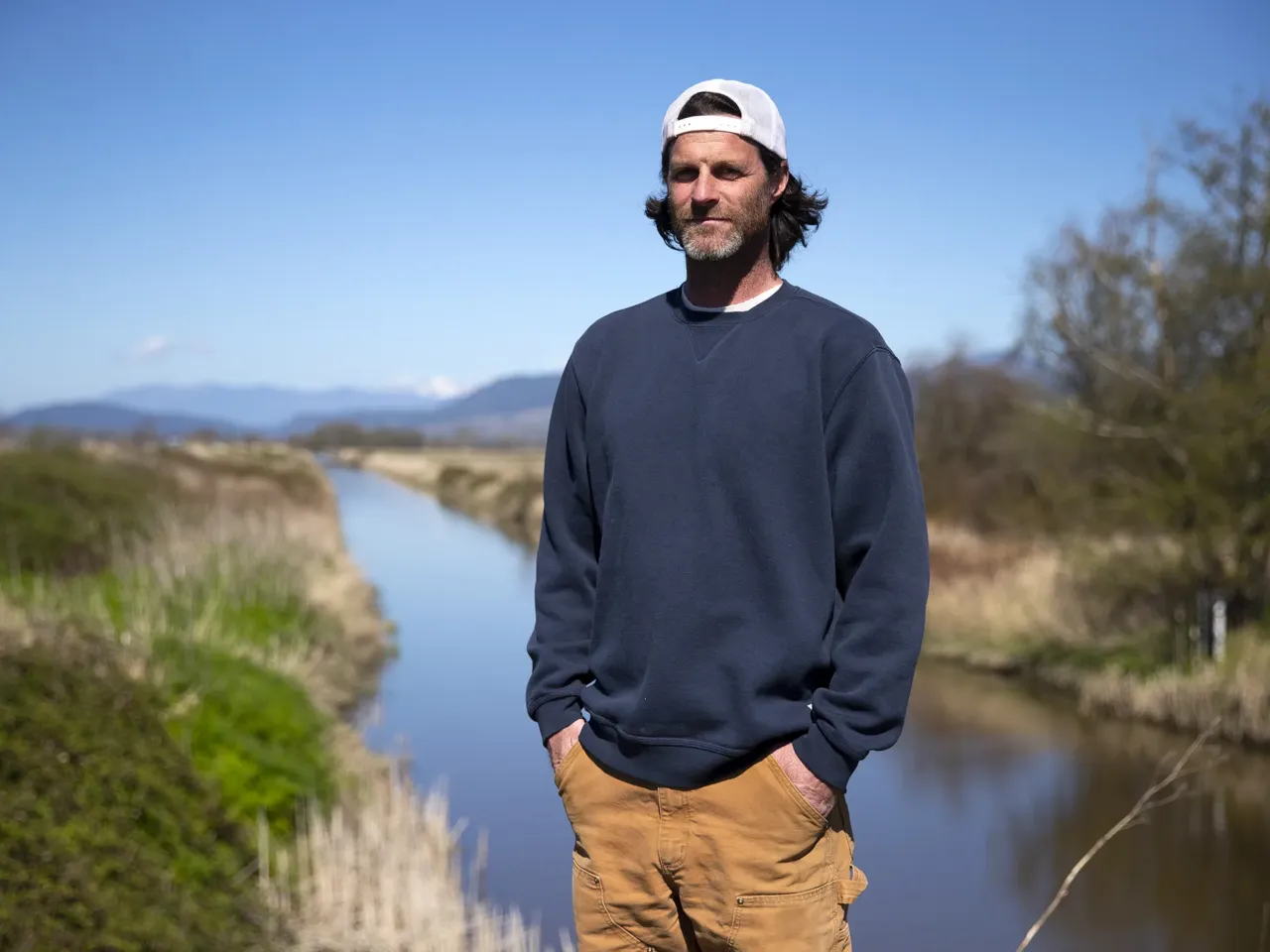 Fifth-generation farmer Tyler Breum stands along the Tom Moore Slough levee, near Big Ditch, close to his family's farmland on April 8, 2026, near Stanwood, Wash.