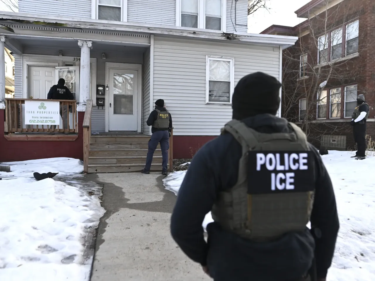 ICE agents approach a house before detaining two people on Jan. 13 in Minneapolis.
