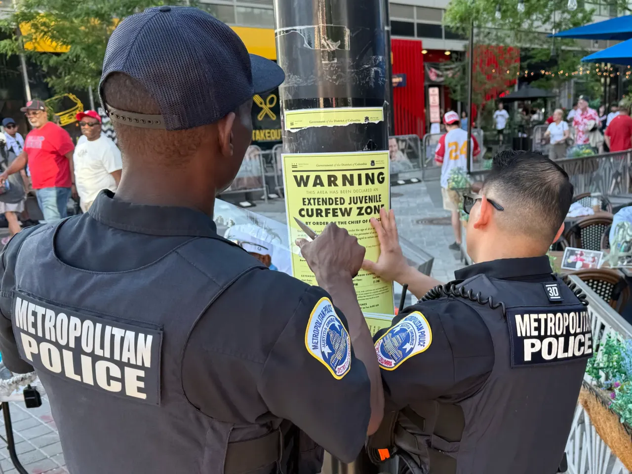 Washington D.C. Metropolitan Police officers place signage on a light pole informing the public that the area near the Nationals Park is under designate targeted juvenile curfew zone for youth under the age of 18.