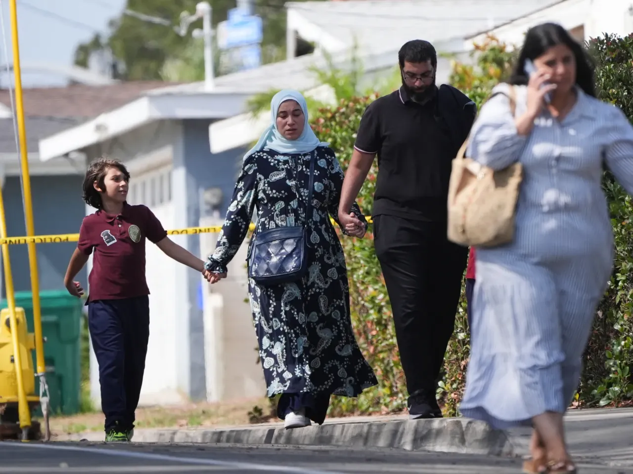 People hold hands near the scene of a shooting outside the Islamic Center of San Diego on Monday.