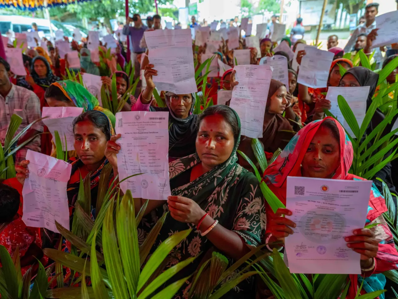 July 1, 2025. Sirajganj, Bangladesh Mothers who lacked birth certificates for themselves and family members hold up the newly obtained documents after a drive in Dhamainagar Union, part of a campaign to get people to register so they are eligible for social safety new programs.