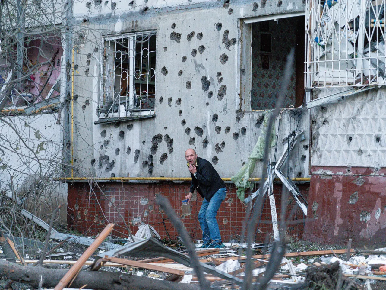 A man cowers outside a damaged building in Kyiv after Russia's latest attack.