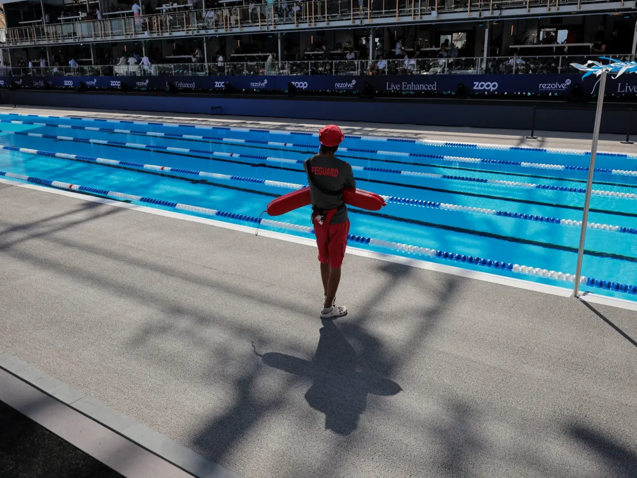 A lifeguard overlooks an outdoor swimming pool.