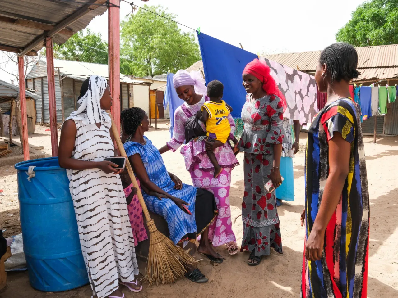 A plan to get lifesaving food to hungry kids was working well -- until it wasn't 1 Women gather around Yacine Lo and her children in the courtyard of their home.