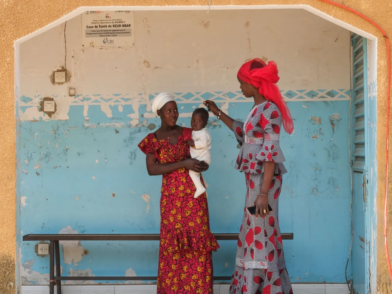 A plan to get lifesaving food to hungry kids was working well -- until it wasn't 3 Adama Faye, a community health worker, stands outside the entry to the small village clinic with Ndiolle Diouf and her son.