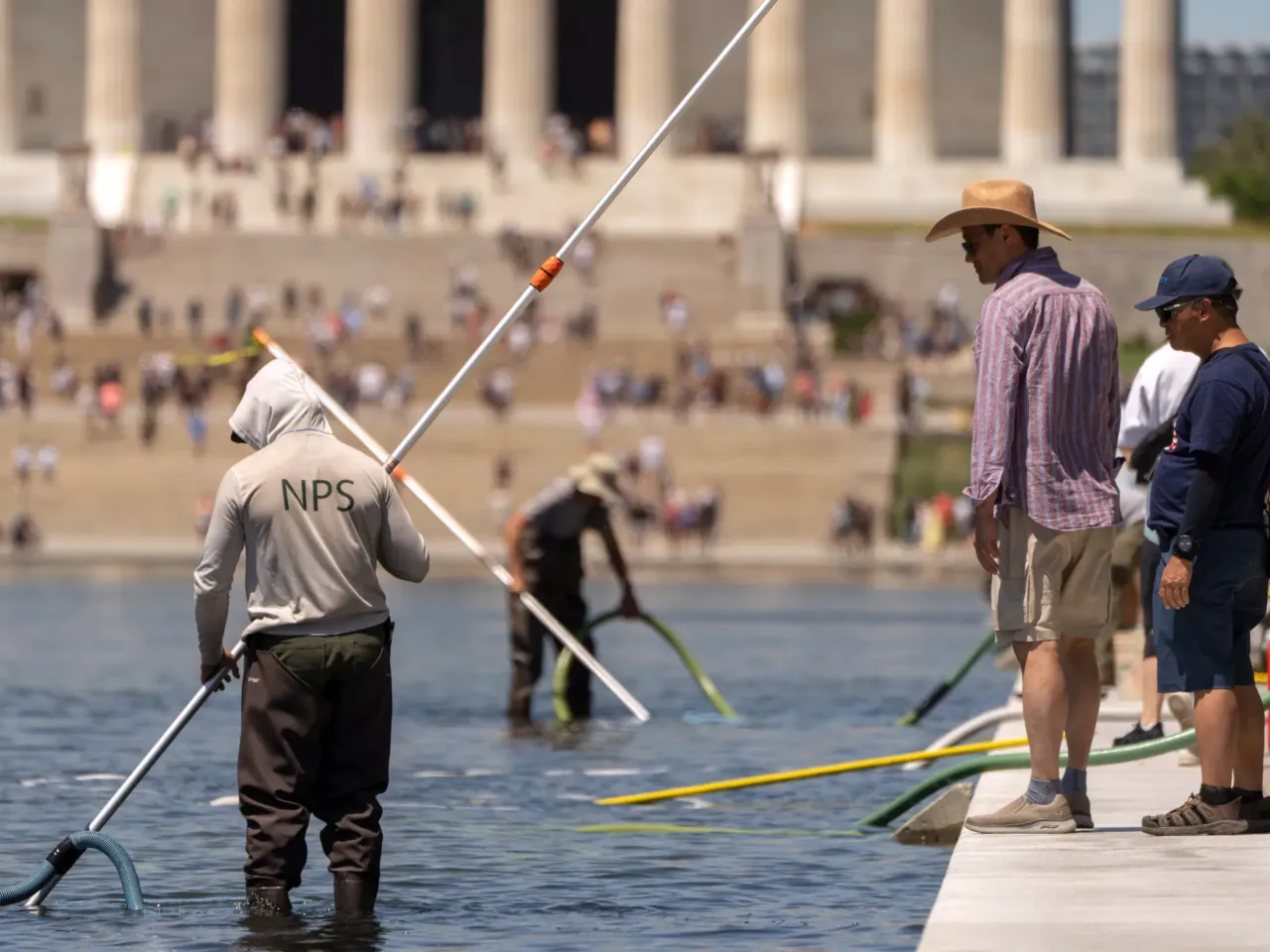 Visitors watch as National Park Service employees use vacuums to clean the Lincoln Memorial Reflecting Pool, Saturday, June 20, 2026, in Washington.