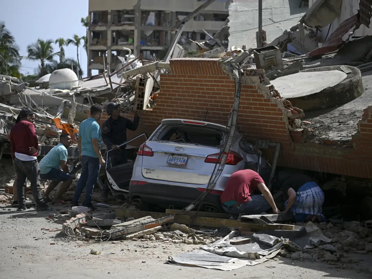 People search through the rubble around a car trapped beneath the collapsed remains of a residential building following an earthquake in Catia La Mar, La Guaira state, about 30 km northwest of Caracas.
