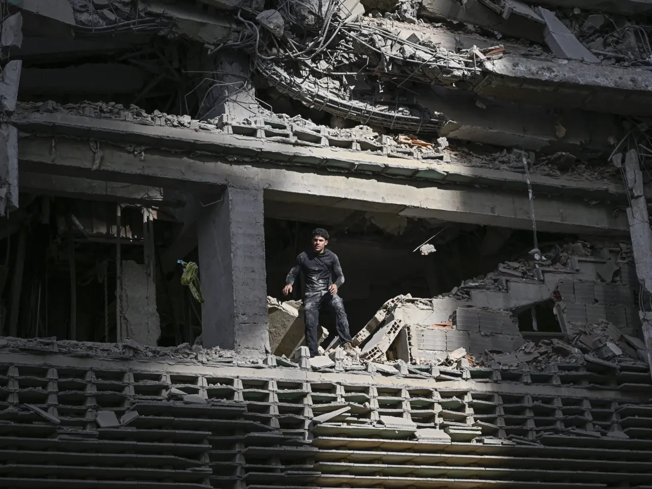 A man looks out from a damaged apartment building following an earthquake.