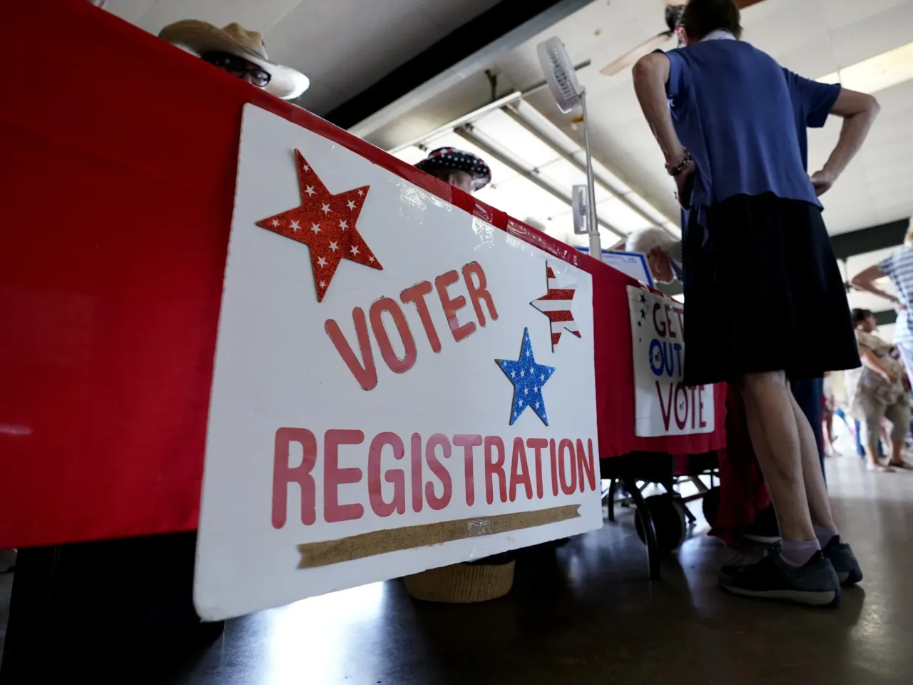People stand near a voter registration table at a 2022 event in Fredericksburg, Texas.