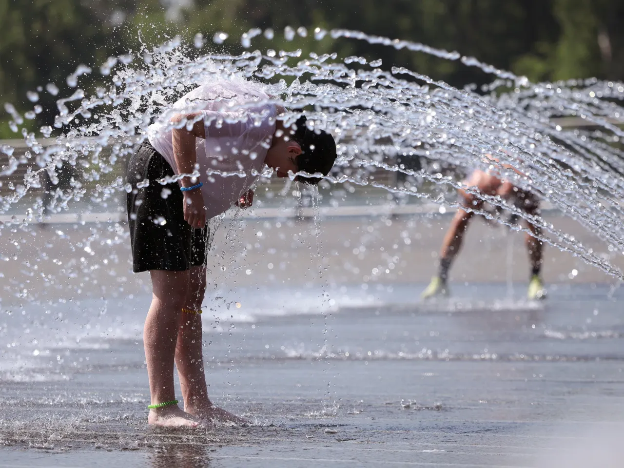 The days are hot, but so are the nights. That's a problem, experts say 1 People cool off in a fountain at the Georgetown Waterfront Park on Thursday.