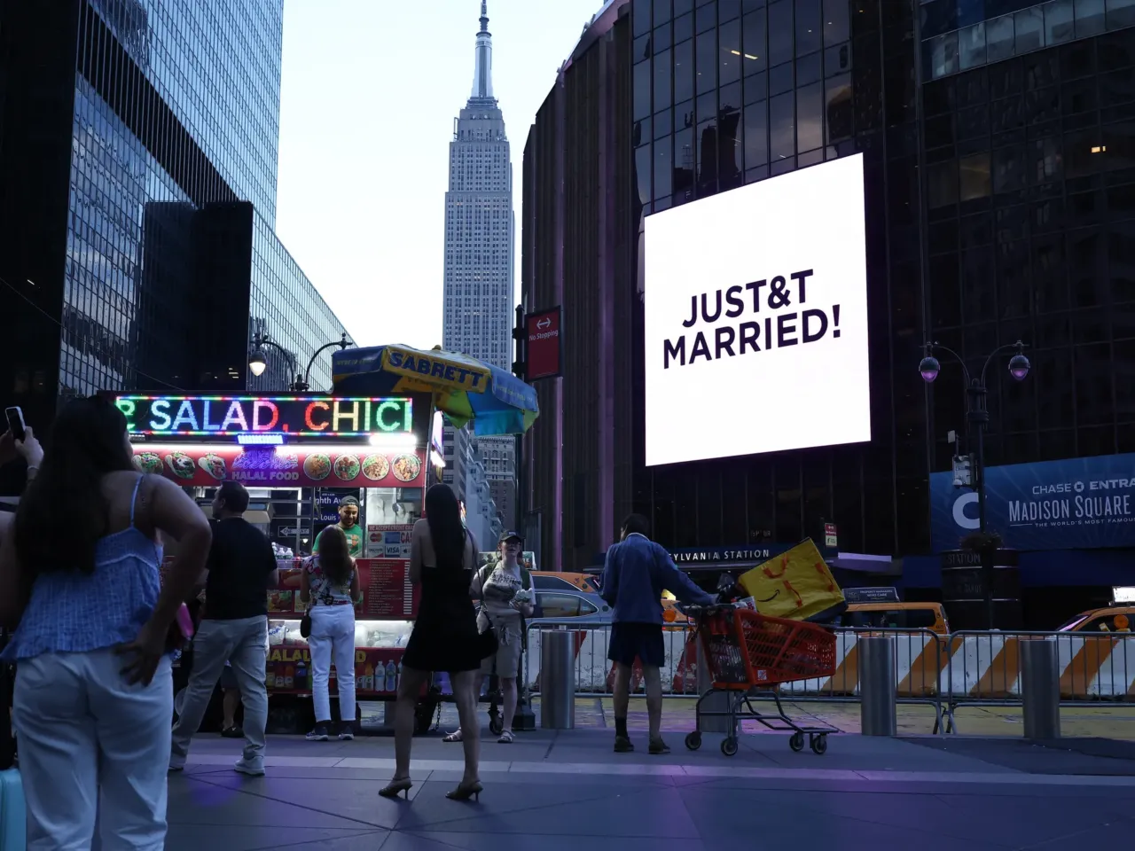 The Empire State Building is seen in the distance as people take photos of a giant screen showing the message "JUST&T MARRIED!" (T&T for Taylor and Travis) outside Madison Square Garden, where wedding celebrations of pop singer Taylor Swift and Travis Kelce of the Kansas City Chiefs were held, in New York City on Friday.