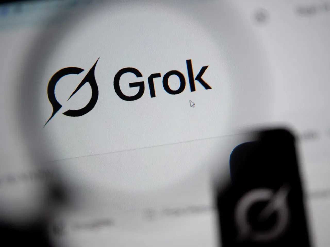 In this photo illustration, the Grok website is seen through a magnifying glass on a computer screen on February 12, 2026. Grok is the AI chatbot built by Elon Musk's SpaceXAI, formerly known as xAI. A class action lawsuit filed against SpaceXAI and Stability AI alleges the companies' AI tools were used to make sexually explicit images of children.