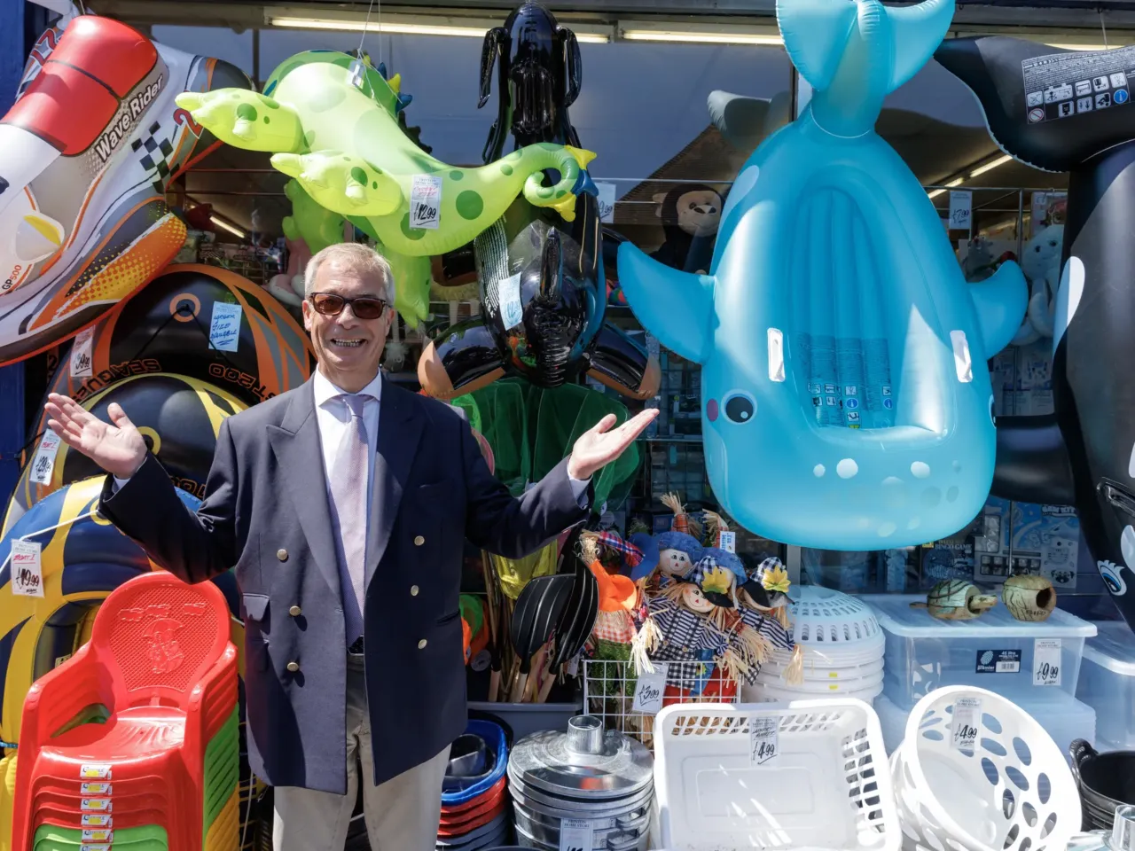 Reform UK leader Nigel Farage stops outside a bucket and spade shop for a photograph while speaking to members of the public on the High Street on July 8, 2026, in Frinton-on-Sea, England.
