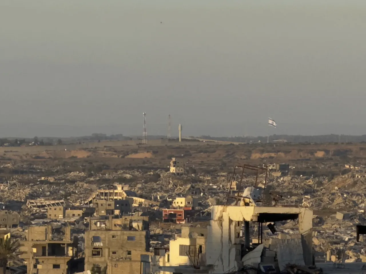 9 months into a ceasefire, Israel now controls nearly 70% of Gaza 5 A large Israeli flag waves in the distance over a landscape of destruction and debris in Gaza near the border with Israel.