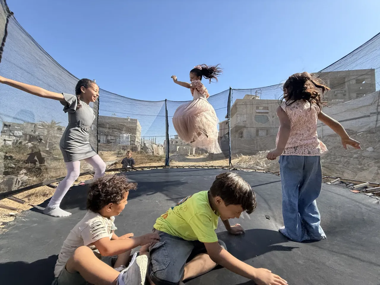 Palestinian children leap into the air while playing on a trampoline in northern Gaza's militarized orange zone of Beit Lahia, on May 31.