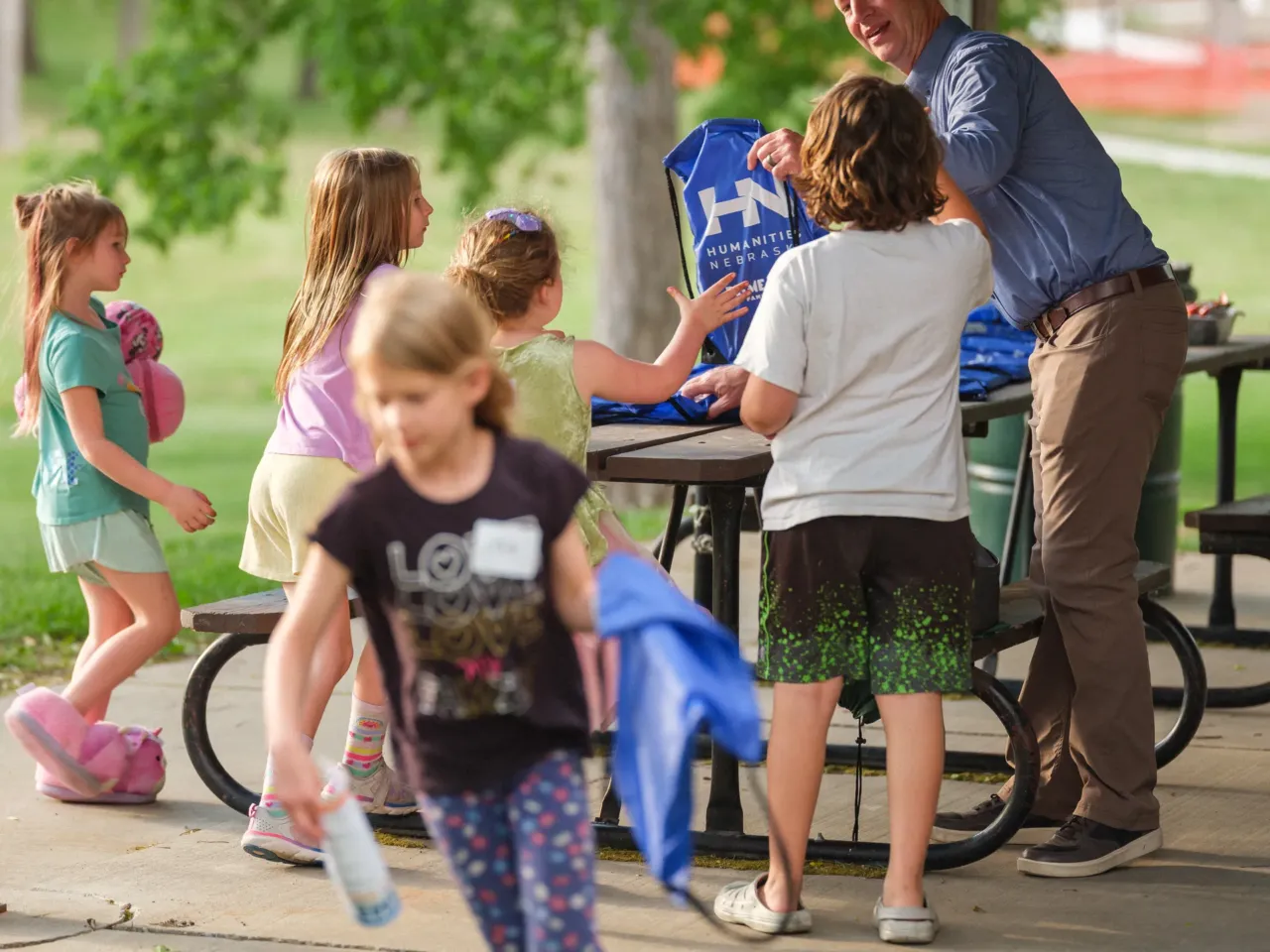 This unusual, Johnny Carson-backed fund has helped Nebraska arts survive — until now 2 Chris Sommerich, Executive Director of Humanities Nebraska, hands out bags to students during Prime Time Family Reading at Henry Park in Lincoln, Neb. on May 14, 2026. The program was led by a storyteller and discussion leader for underserved children and their families to read and discuss award-winning children's books.