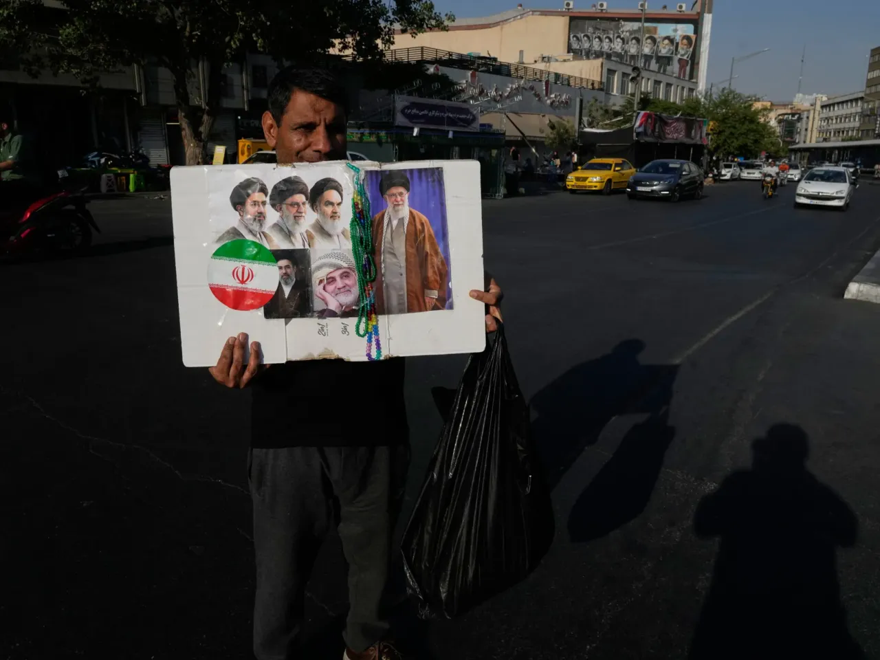 A man displays a placard with portraits of the current and late supreme leaders and the late Revolutionary Guard Gen. Qassem Soleimani at the Islamic Revolution Square in downtown Tehran, Iran, Saturday, July 18, 2026.